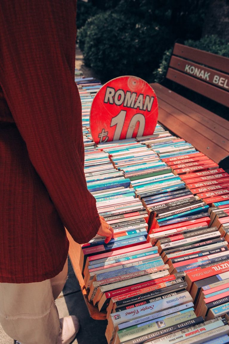 Person browsing books at an outdoor book stall with vibrant roman signage and pricing.