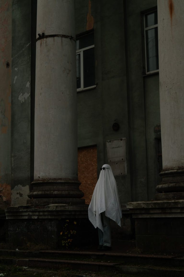 Spooky scene of a ghostly figure in front of an abandoned building's columns, perfect for Halloween themes.