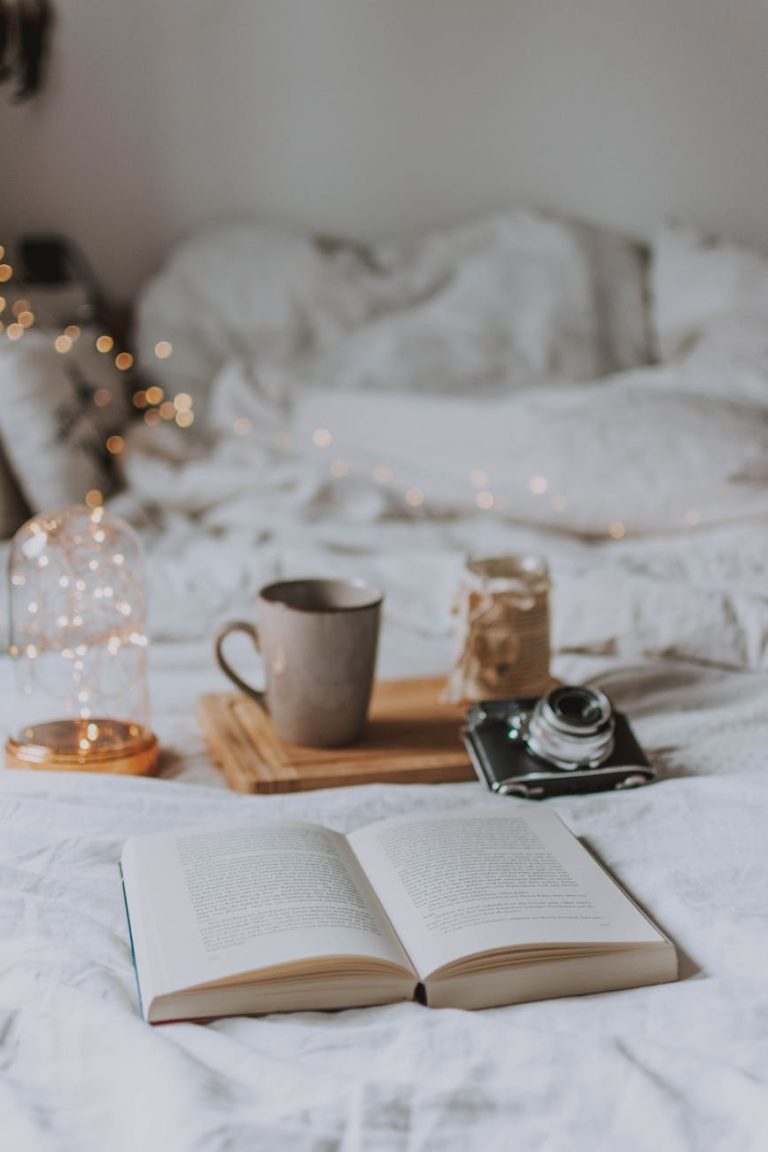 A cozy bedroom scene with coffee, books, and warm lighting, perfect for relaxation.