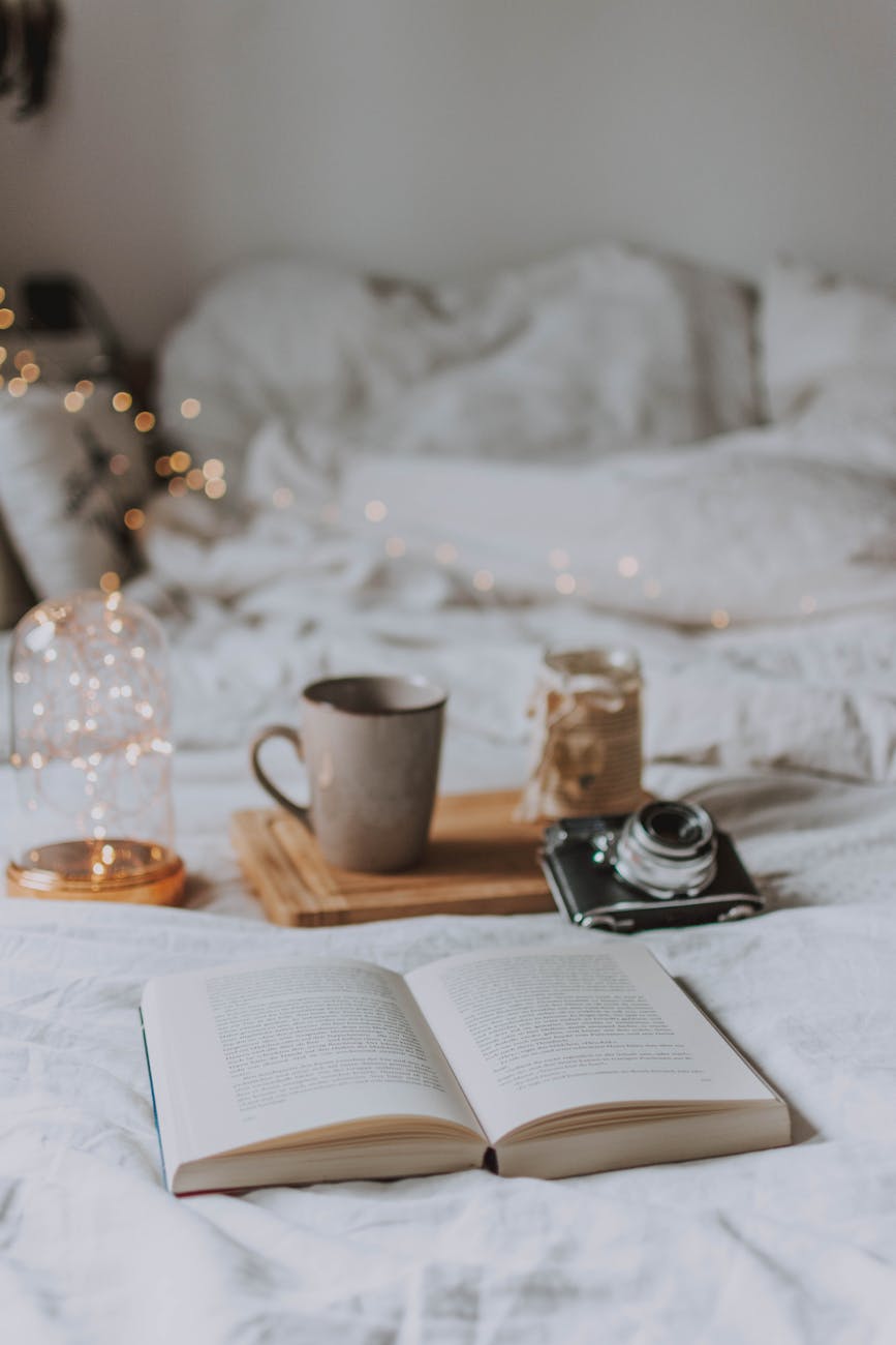 A cozy bedroom scene with coffee, books, and warm lighting, perfect for relaxation.