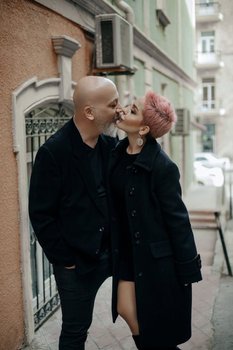 A stylish couple sharing a romantic kiss outdoors in an urban setting in Azerbaijan.
