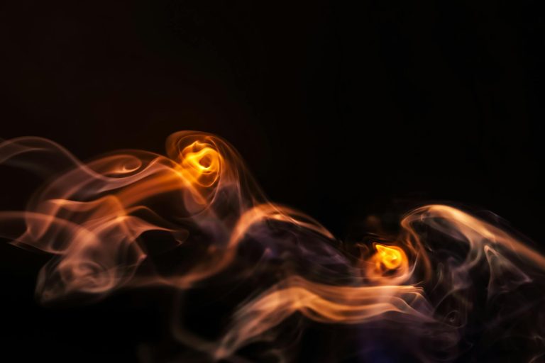 Abstract image capturing the swirling motion of fire and smoke against a dark background.