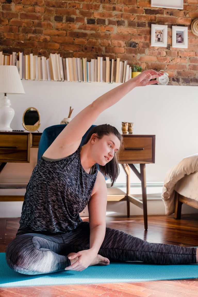 Adult woman in activewear stretching on a yoga mat indoors.