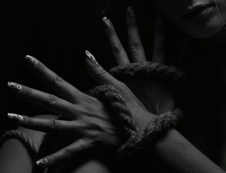 Black and white photo of hands intertwined with rope. Dramatic and artistic close-up.