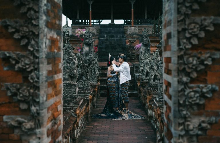 Asian couple in traditional wear at a temple, symbolizing cultural heritage and love.