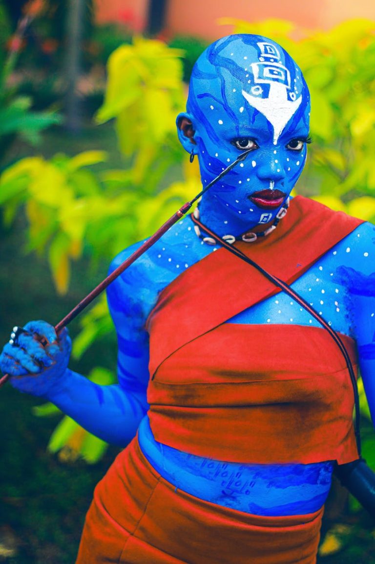 Vivid blue body paint art inspired by fictional characters in a natural setting.