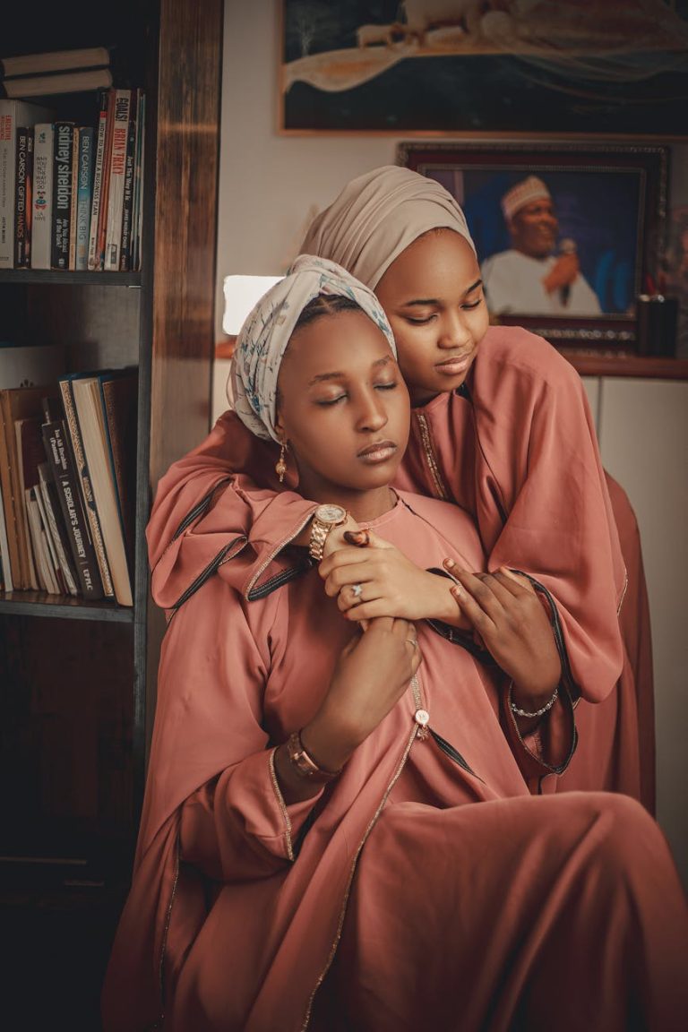 Two women sharing an intimate moment, wearing hijabs, indoors.