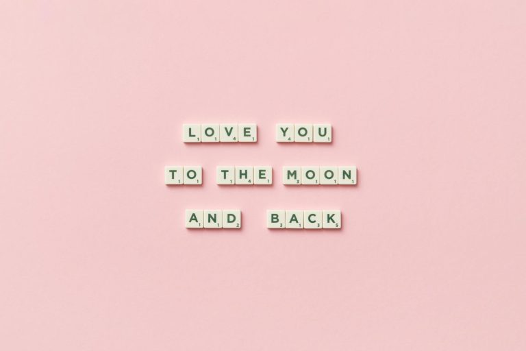 Letter tiles spelling 'Love You to the Moon and Back' on a pink background.
