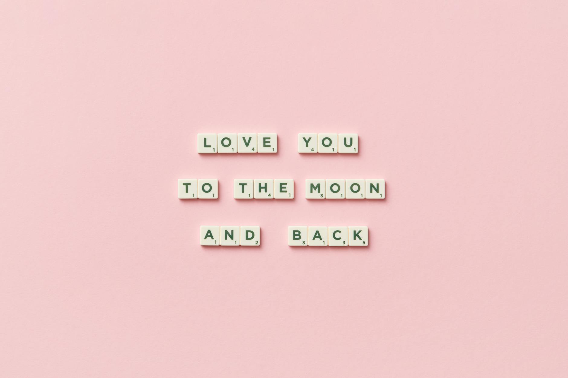 Letter tiles spelling 'Love You to the Moon and Back' on a pink background.